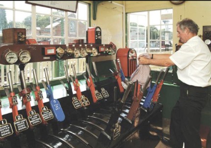 Signalman working the red and blue levers inside the signal box