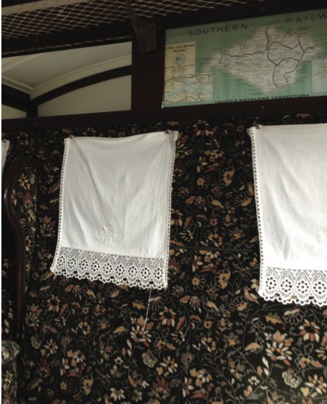 Close-up of vintage carriage upholstery featuring dark floral fabric and white lace antimacassars