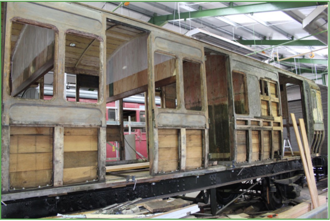 A wooden railway carriage undergoing structural restoration inside the engineering workshop